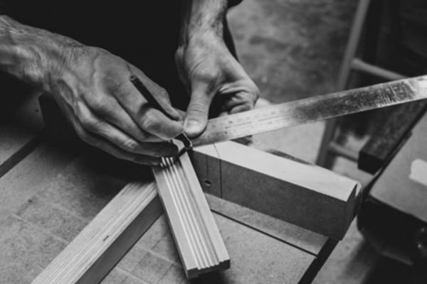 Black and white picture of person measuring wood